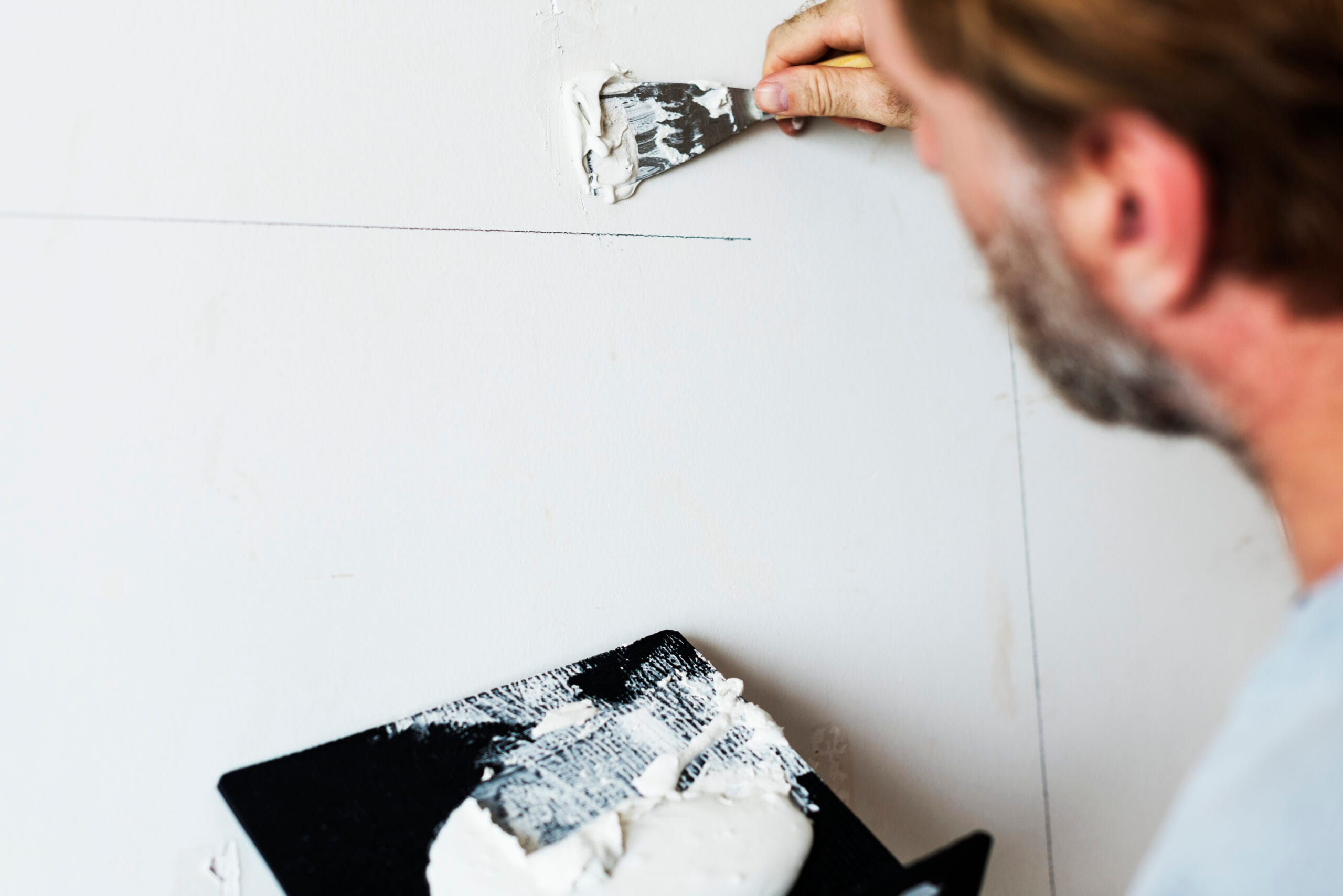 man repairing cracks in the drywall